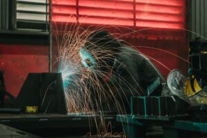 welding respirator Thailand — professional welder surrounded by fume in industrial workshop